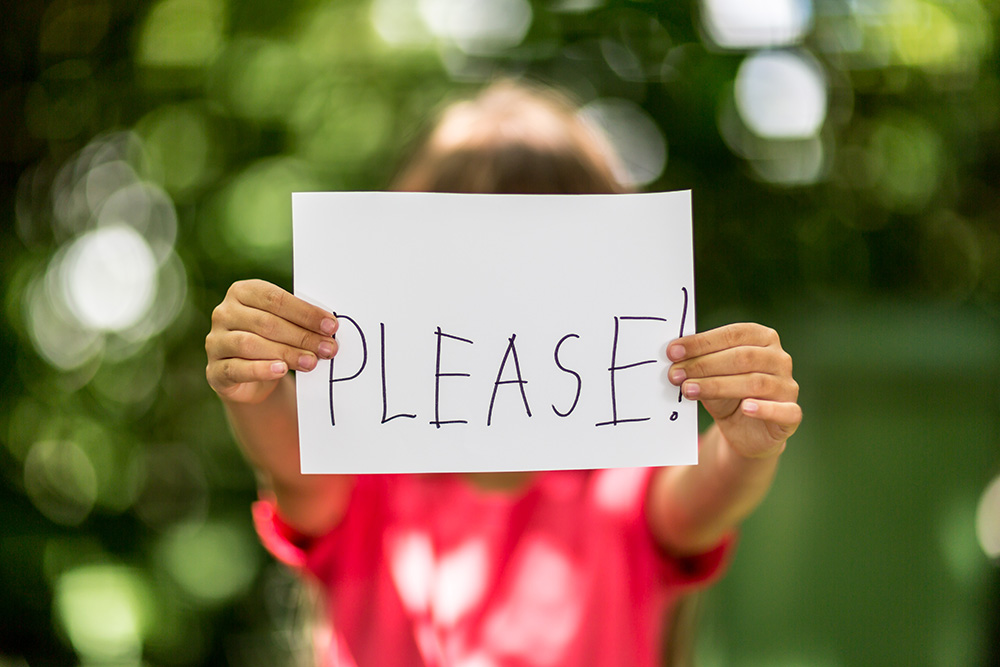 Learn why manners matter image of kid holding sign saying please with Kim Feeney at Butterfly Beginnings Play Therapy in Davenport, IA