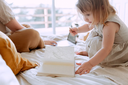 Balancing work and baby image of toddler on bed with parent working on computer with How to Balance Work and a Baby with Butterfly Beginnings Counseling Therapy Kids Davenport, Iowa