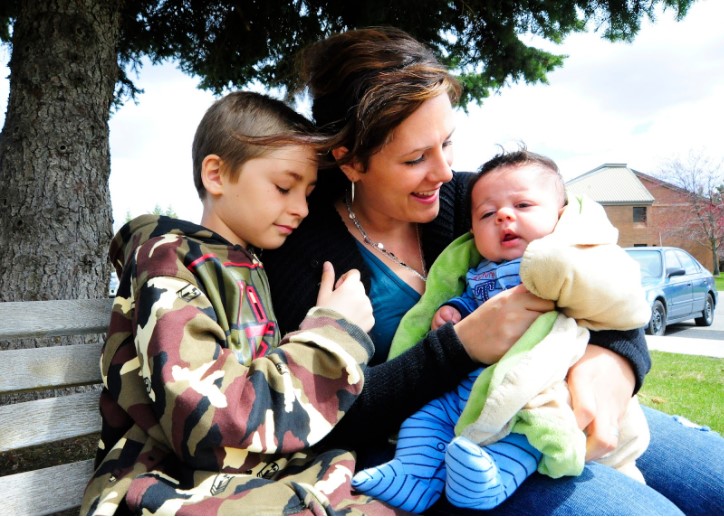 Image of mom and kids cuddling on a bench outdoors for butterfly beginnings play therapy in iowa blog: are you enabling your child's anxiety?